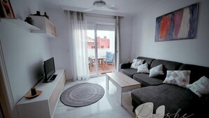 Moderni olohuone, jossa on sohva, sohvapöytä, televisio ja kattotuuletin.