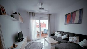 Ein modernes Wohnzimmer mit einer Couch, einem Couchtisch, einem Fernseher und einem Deckenventilator.