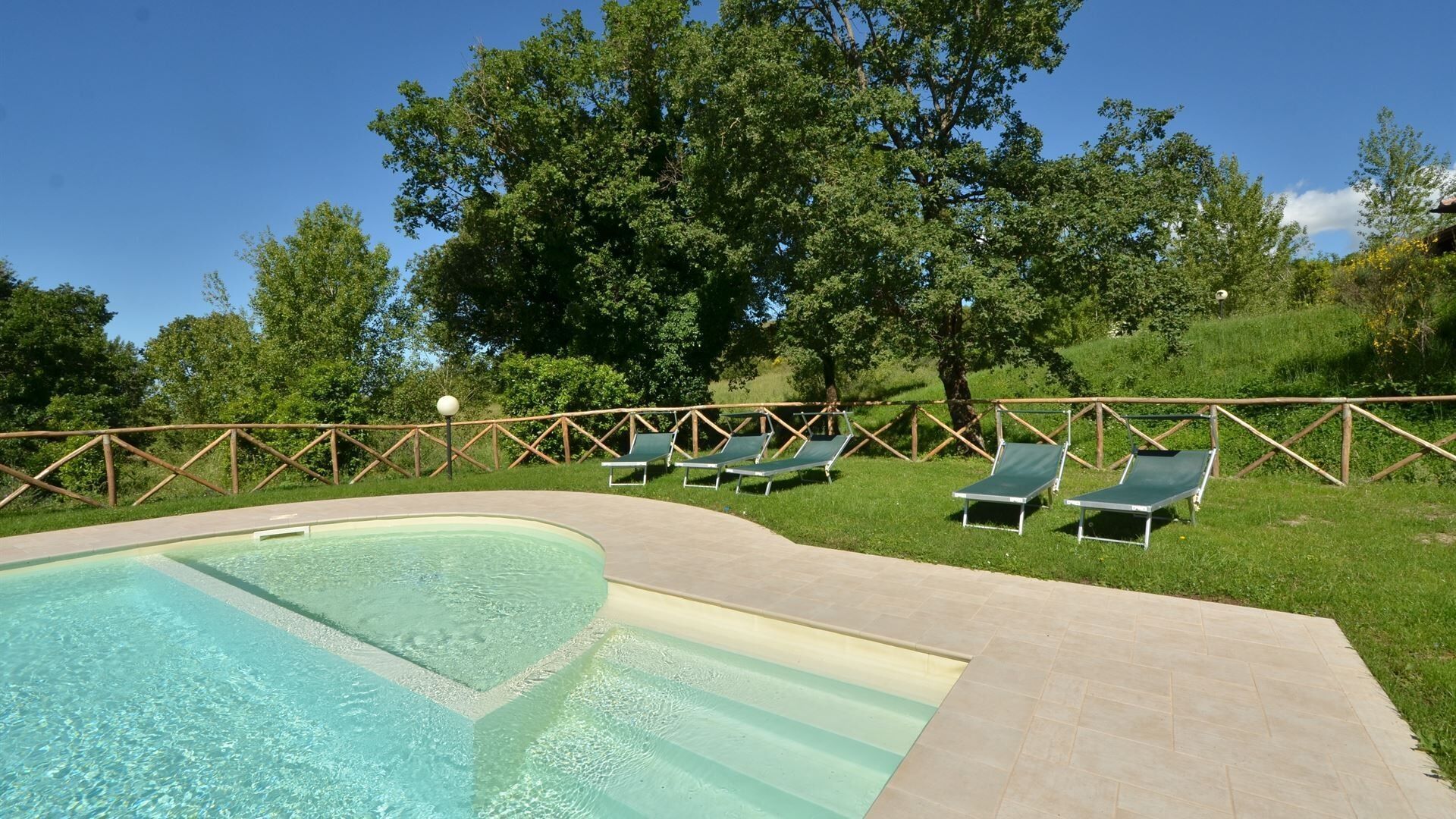 A swimming pool with lounge chairs and a wooden fence.
