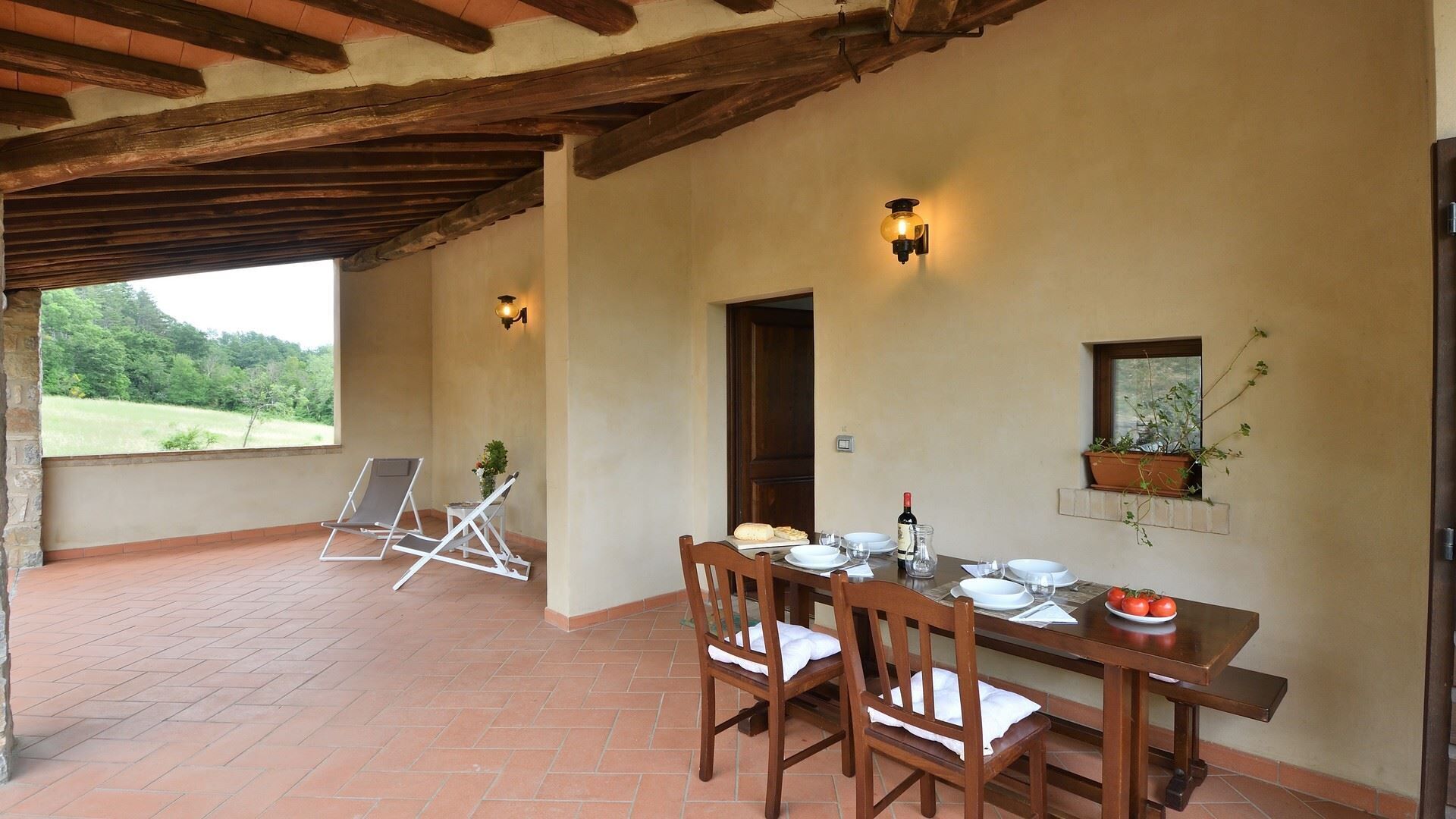 A dining area with a wooden table set for two, two chairs, and a view of the outdoors.