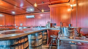 A bar area with wooden barrels, a stainless steel sink, and hanging light fixtures. - Quincy Home on Lavender Farm w/ River Views! (Quincy)