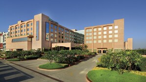 A modern hotel with a symmetrical facade, multiple floors, and a central courtyard with landscaped gardens. - Yashail Hotel Haridwar (Haridwar)