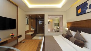 A modern hotel room with a large bed, a flat-screen TV, a desk, and a bathroom visible through an open door. - Yashail Hotel Haridwar (Haridwar)