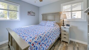 A bedroom with a bed, a nightstand, a lamp, and a ceiling fan.