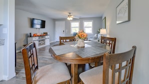A dining area with a round wooden table, four chairs, and a vase with flowers.