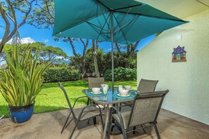 Eine Terrasse im Freien mit Tisch und Stühlen, einem Blumentopf und einem dekorativen Wandelement.
