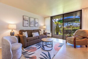 A living room with a sofa, armchairs, a coffee table, and artwork on the wall.
