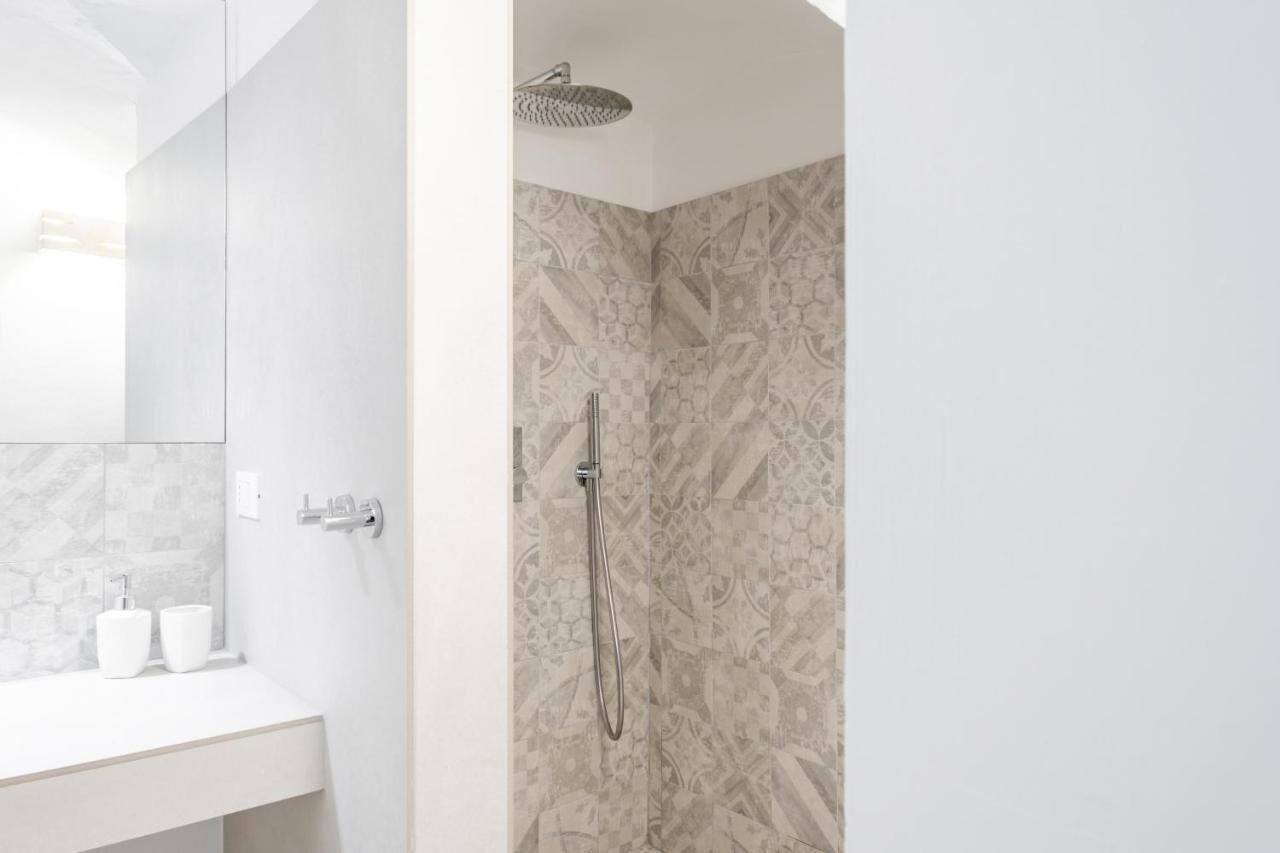 Une salle de bain moderne avec une douche, un lavabo blanc et un miroir.