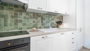A kitchen with white cabinets, a green tiled backsplash, a sink, and a stove. - Trullo Bella Vista With Patio & Parking (Locorotondo)