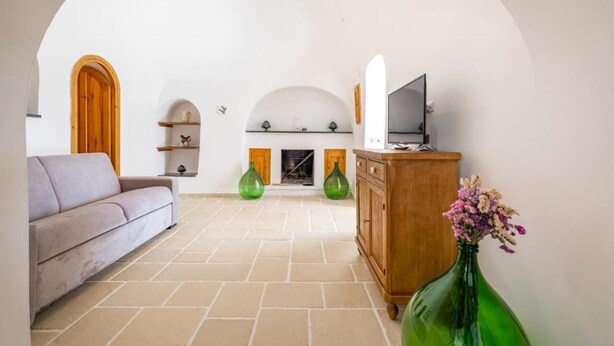 A living room with a sofa, a cabinet, a TV, and a fireplace. - Trullo Bella Vista With Patio & Parking (Locorotondo)