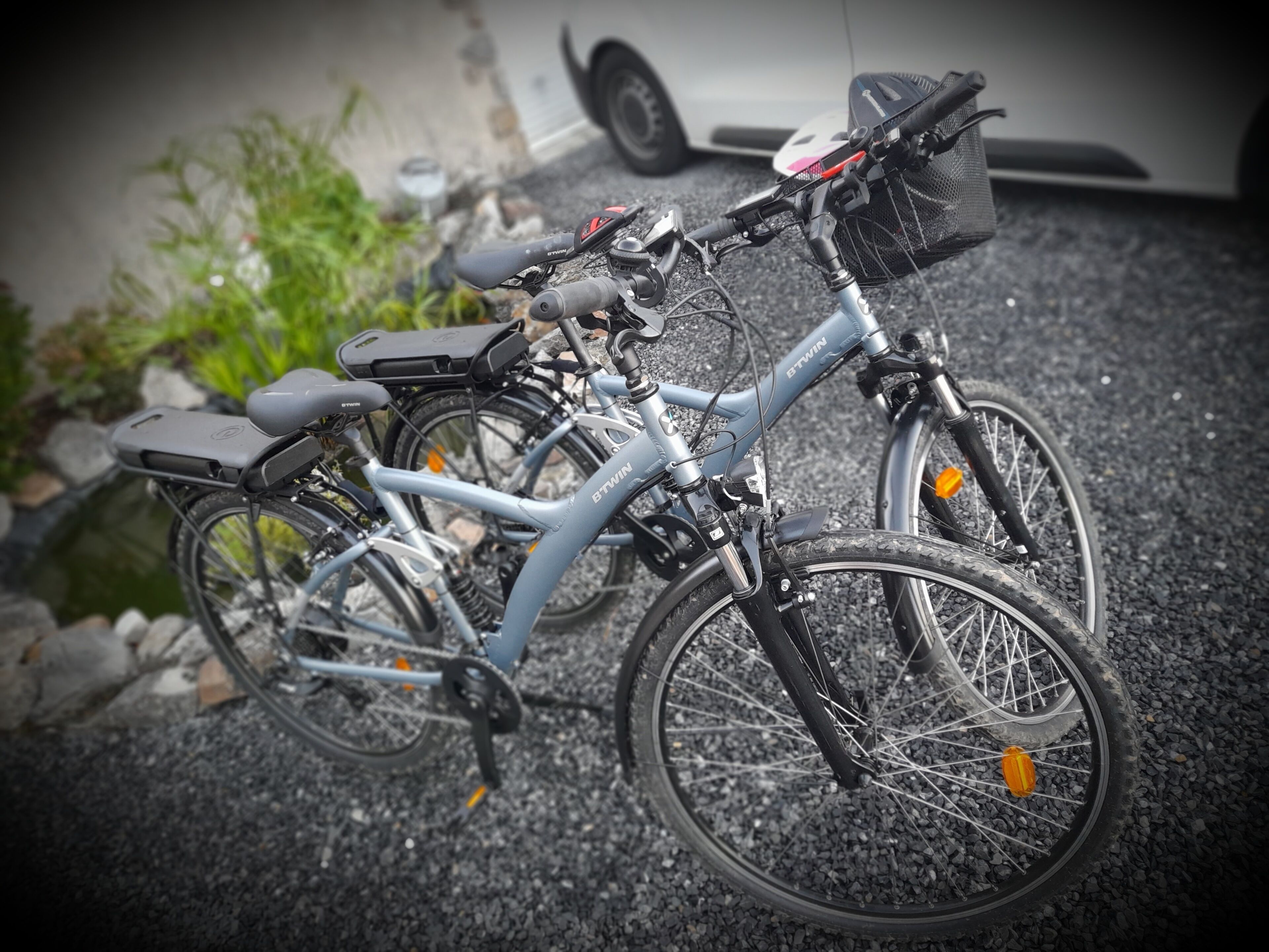Una bicicleta con canasta y alforja estacionada sobre grava.