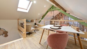 A cozy loft bedroom with a sloped ceiling, a skylight, a wooden staircase, a dining area with a table and chairs, and a small seating area with a chair and a sofa. - Instinct - Jacuzzi, Sauna, Apéritif dînatoire et petit déjeuner (Rocquigny)