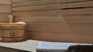 Un sauna avec des panneaux en bois, un banc en bois et un seau en bois.