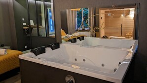Une salle de bain moderne avec une grande baignoire, un miroir et un lit recouvert d’une couverture jaune.