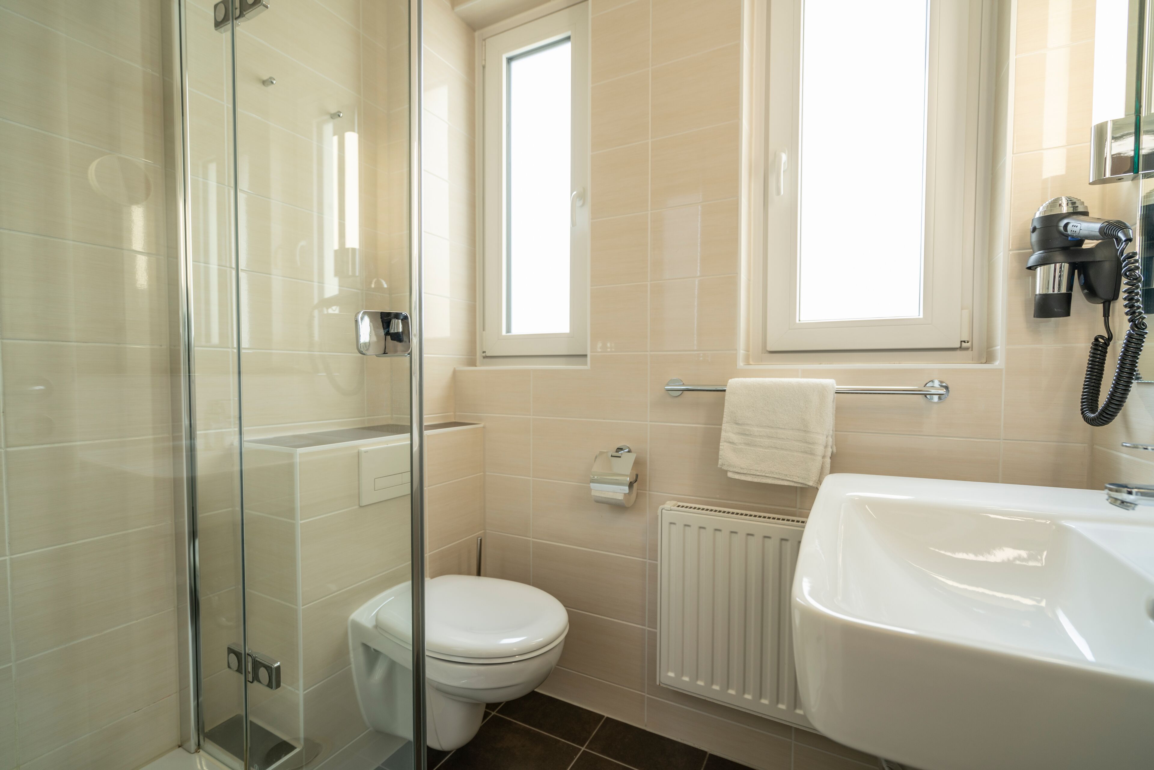 A modern bathroom with a glass shower enclosure, a toilet, a sink, and a towel rack.