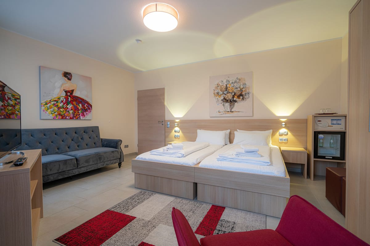 Ein modernes Hotelzimmer mit einem großen Bett, einer Couch, einem Fernseher und Kunstwerken an den Wänden.