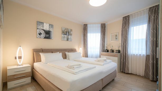 A hotel room with a large bed, bedside tables, a mirror, and artwork on the walls.