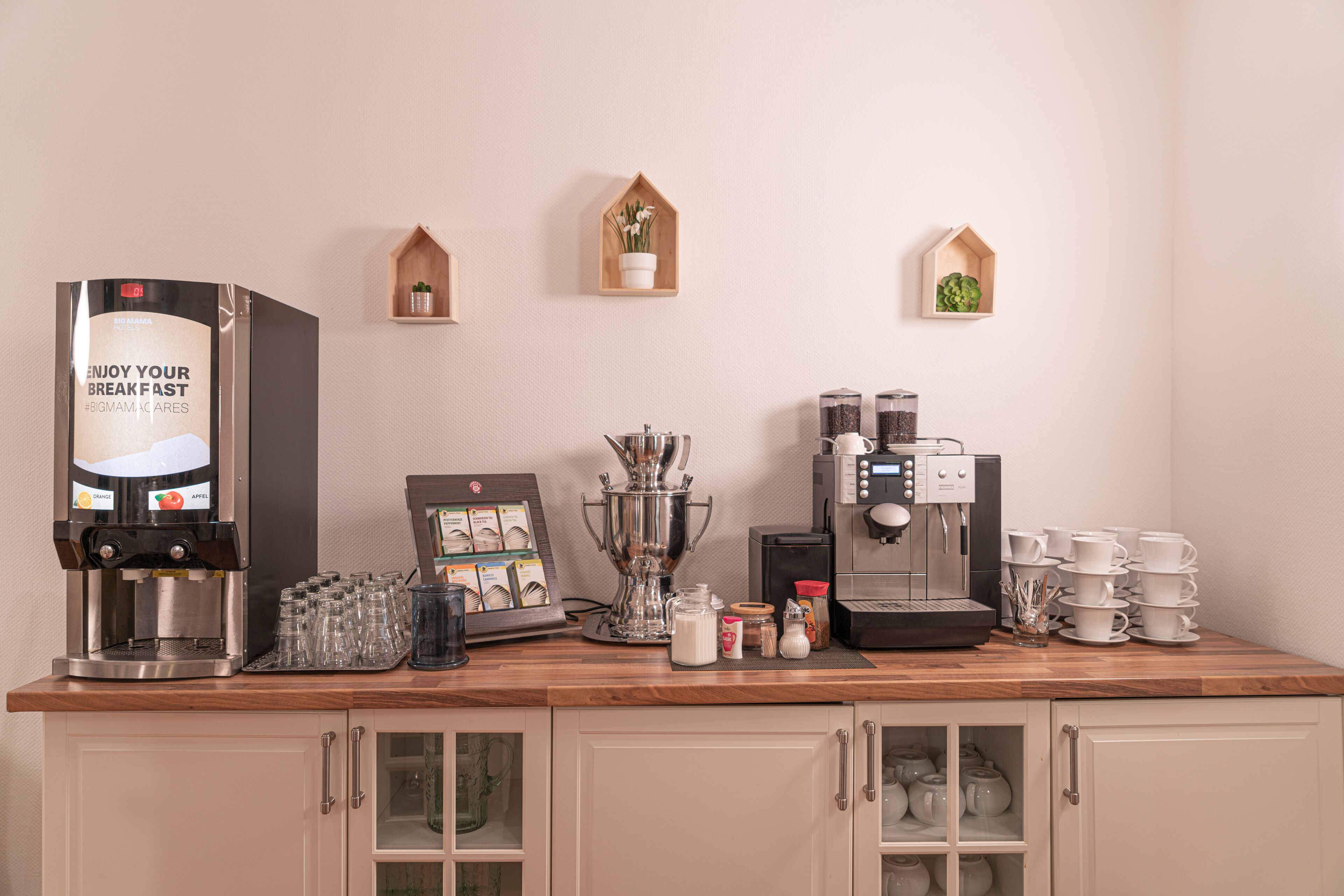 Una kitchenette con una cafetera, tetera y una selección de cápsulas de café.