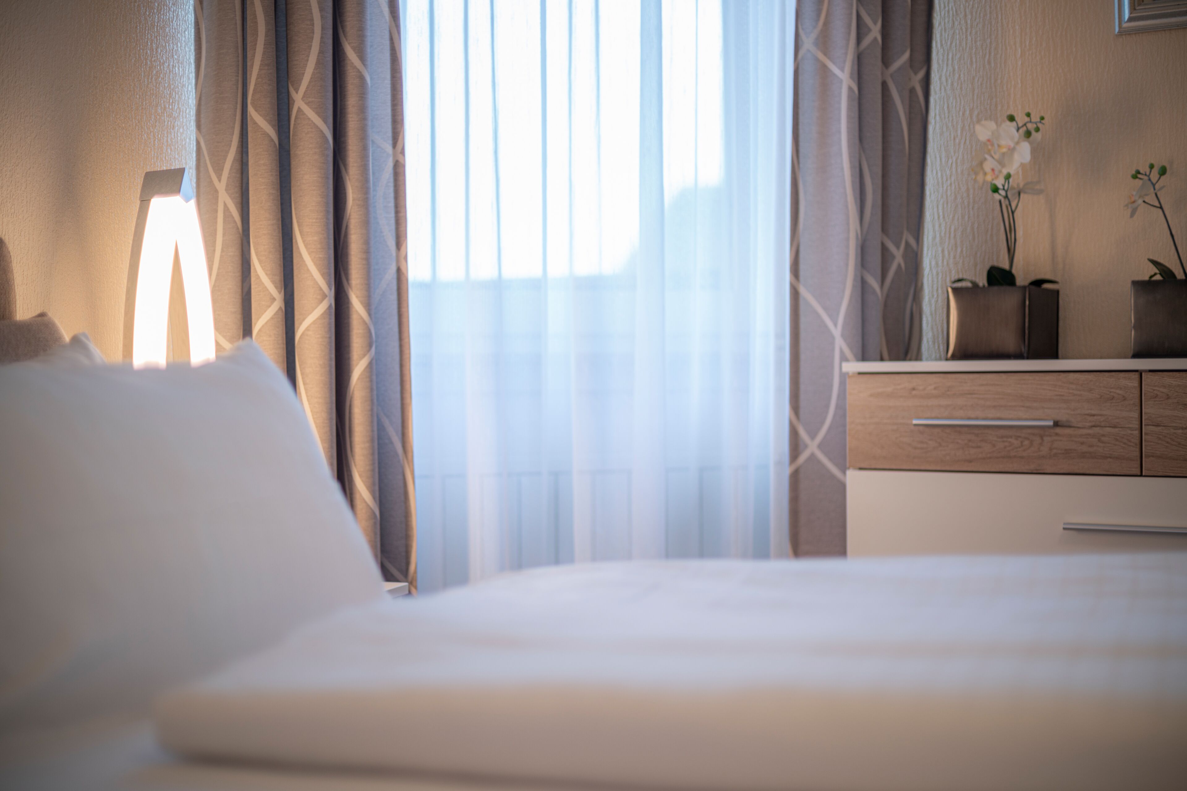 Une chambre d’hôtel avec un lit, une commode et une fenêtre avec des rideaux.