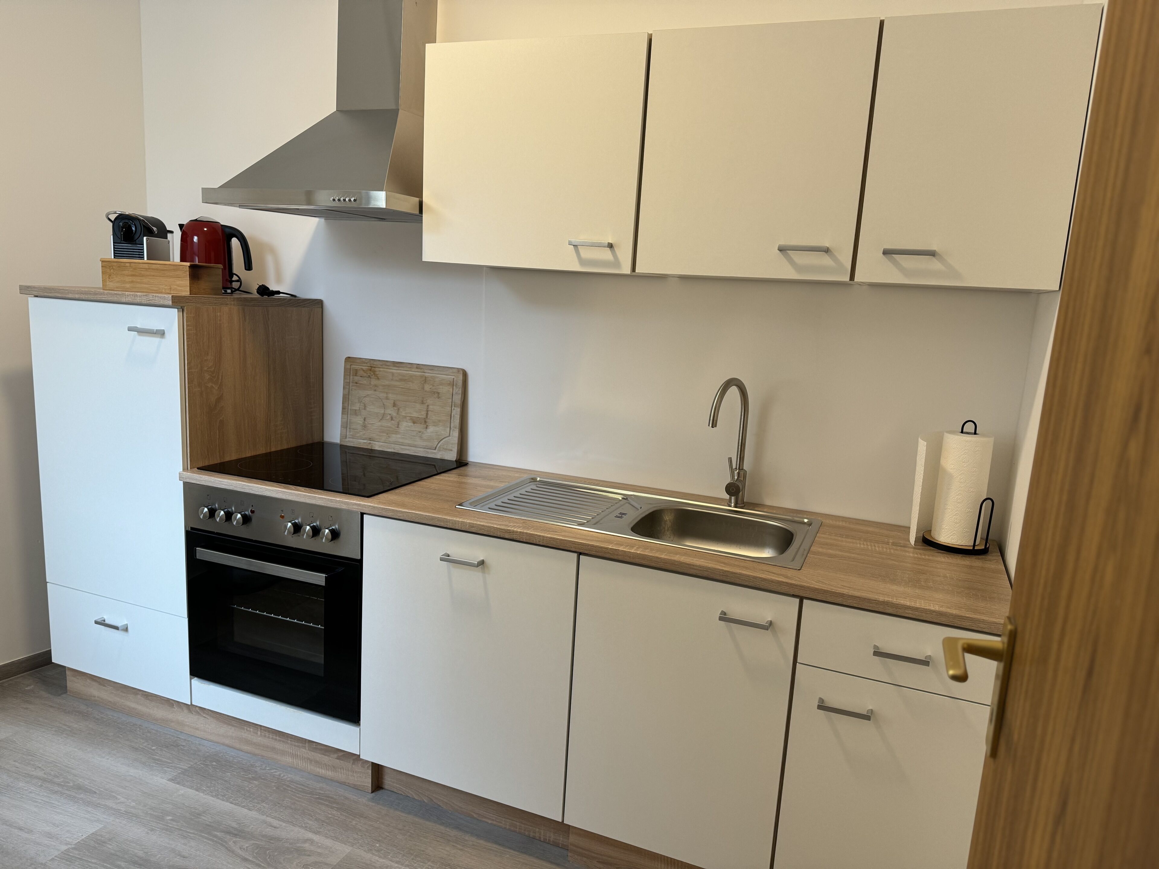 A compact kitchen with a stove, oven, sink, and wooden countertop.
