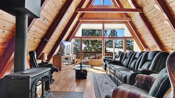 A cozy attic room with a fireplace, leather sofa, and a TV.