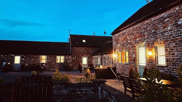 A brick building with multiple windows and a door, surrounded by gravel and plants. - Coast Cottage -  a very spacious, dog friendly, cottage for 4 guests (Bempton)