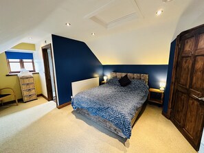 Une chambre à coucher avec un lit, une commode, une chaise et une fenêtre avec des stores.