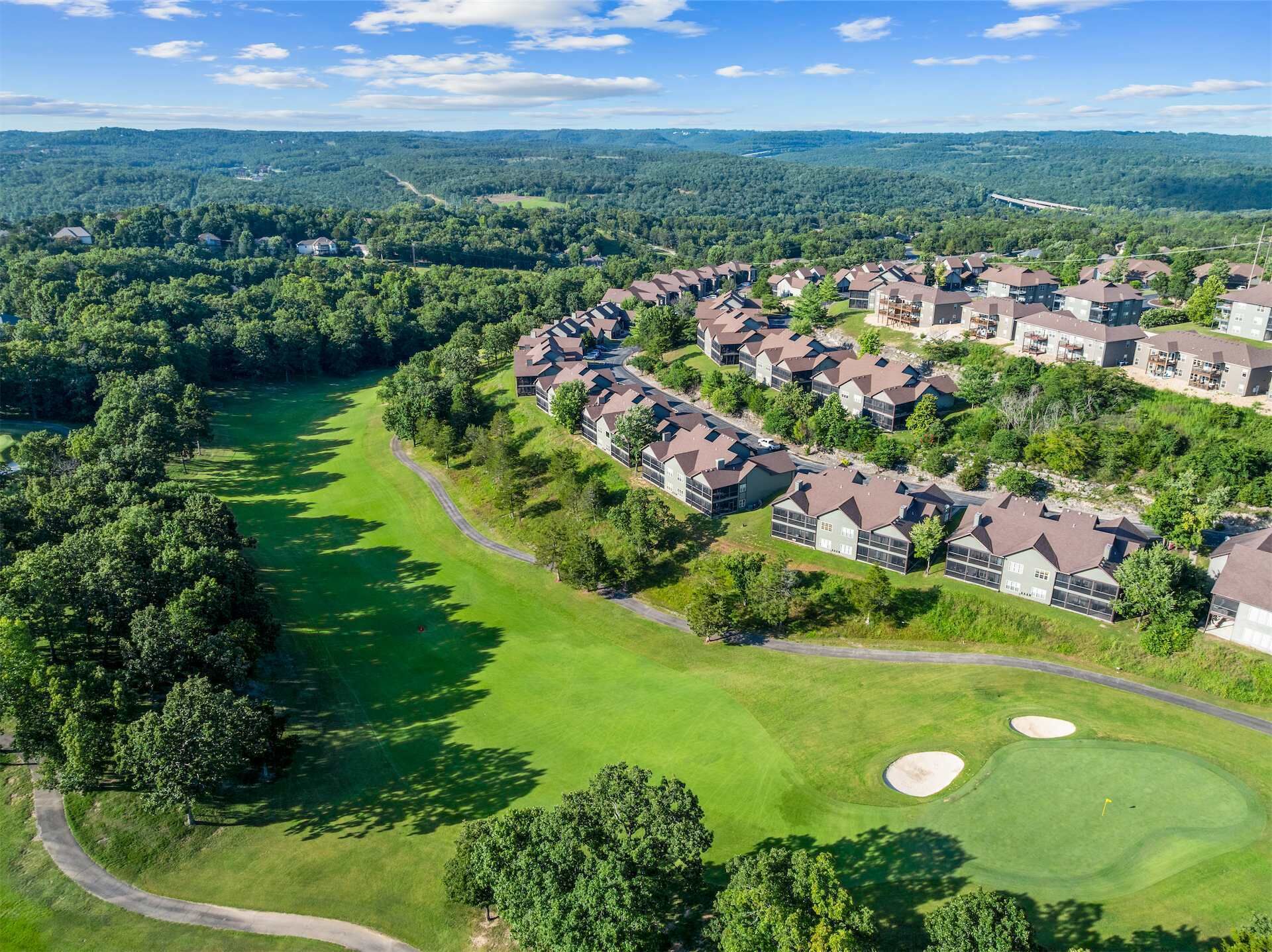 A golf course with a residential area featuring modern houses with sloped roofs.
