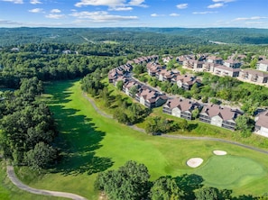 A golf course with a residential area featuring modern houses with sloped roofs.