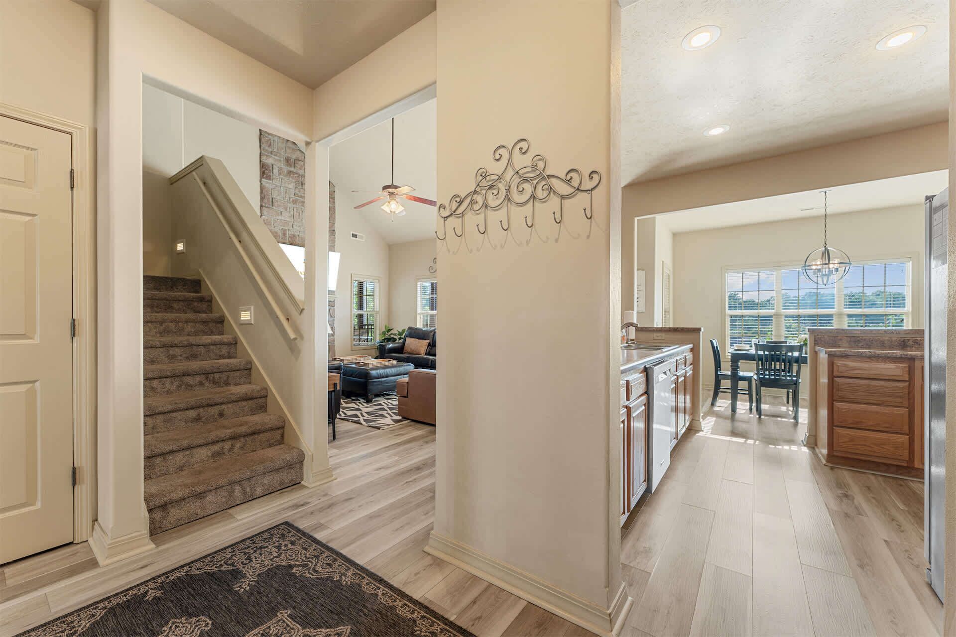 A spacious interior with a staircase leading to a living area, a kitchen with wooden cabinets, and a dining area with a view.
