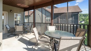 En inglasad uteplats med ett glasbord och stolar, med utsikt över ett bostadsområde.
