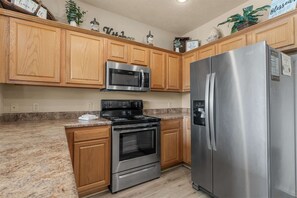 Una cocina con armarios de madera, un refrigerador de acero inoxidable, un microondas y un horno.