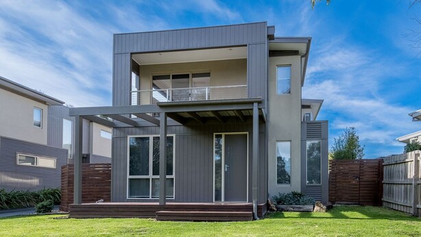 A modern two-story house with a balcony, large windows, and a well-maintained lawn. - Freda Beach Haven, centrally located (Inverloch)