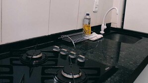 A kitchen with a black stove, white tiles, and a white cabinet.
