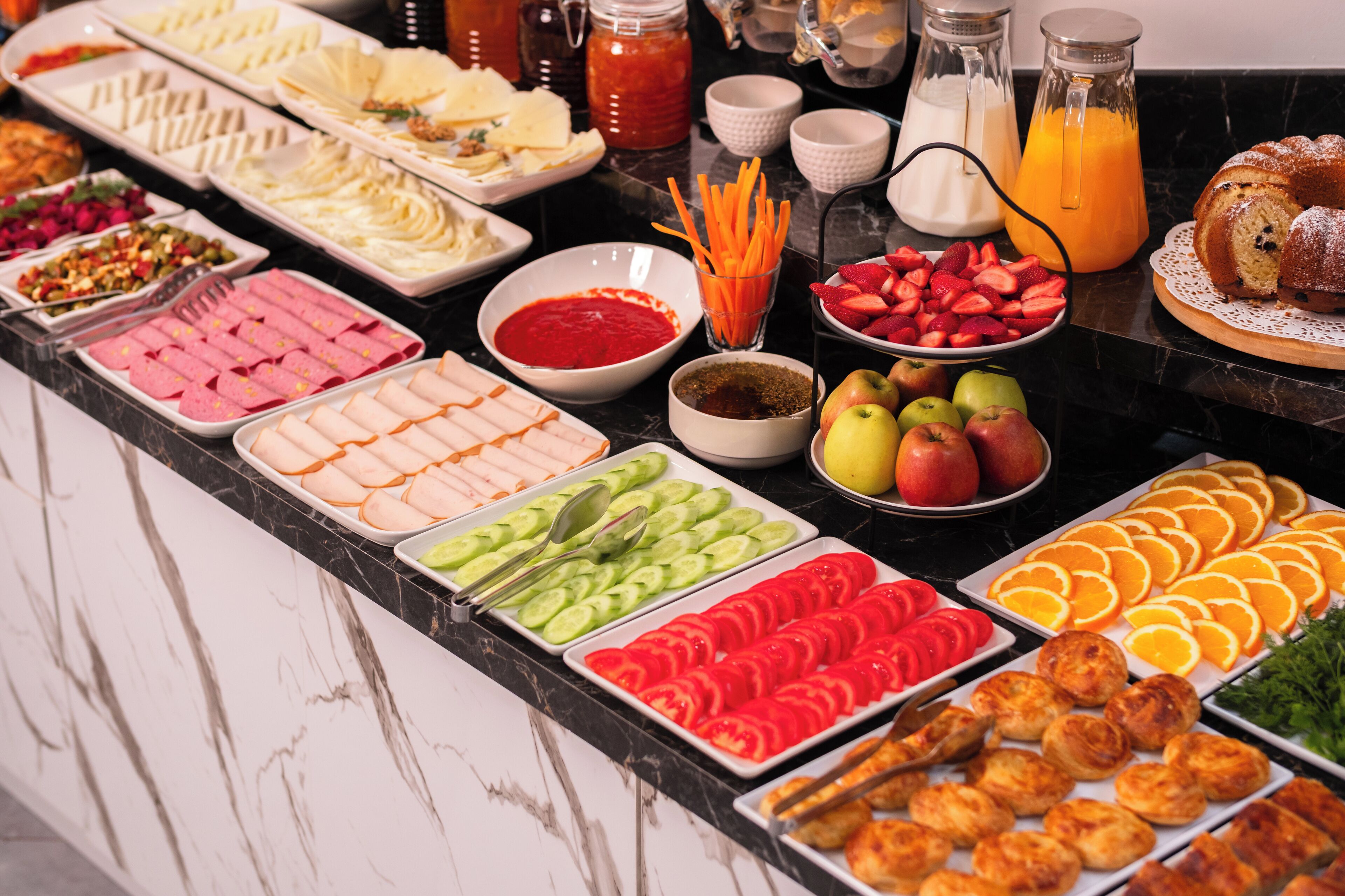 A buffet with various food items including fruits, vegetables, and pastries.