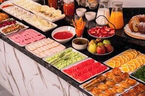 Un bufé con diversos alimentos, entre ellos frutas, verduras y pasteles.