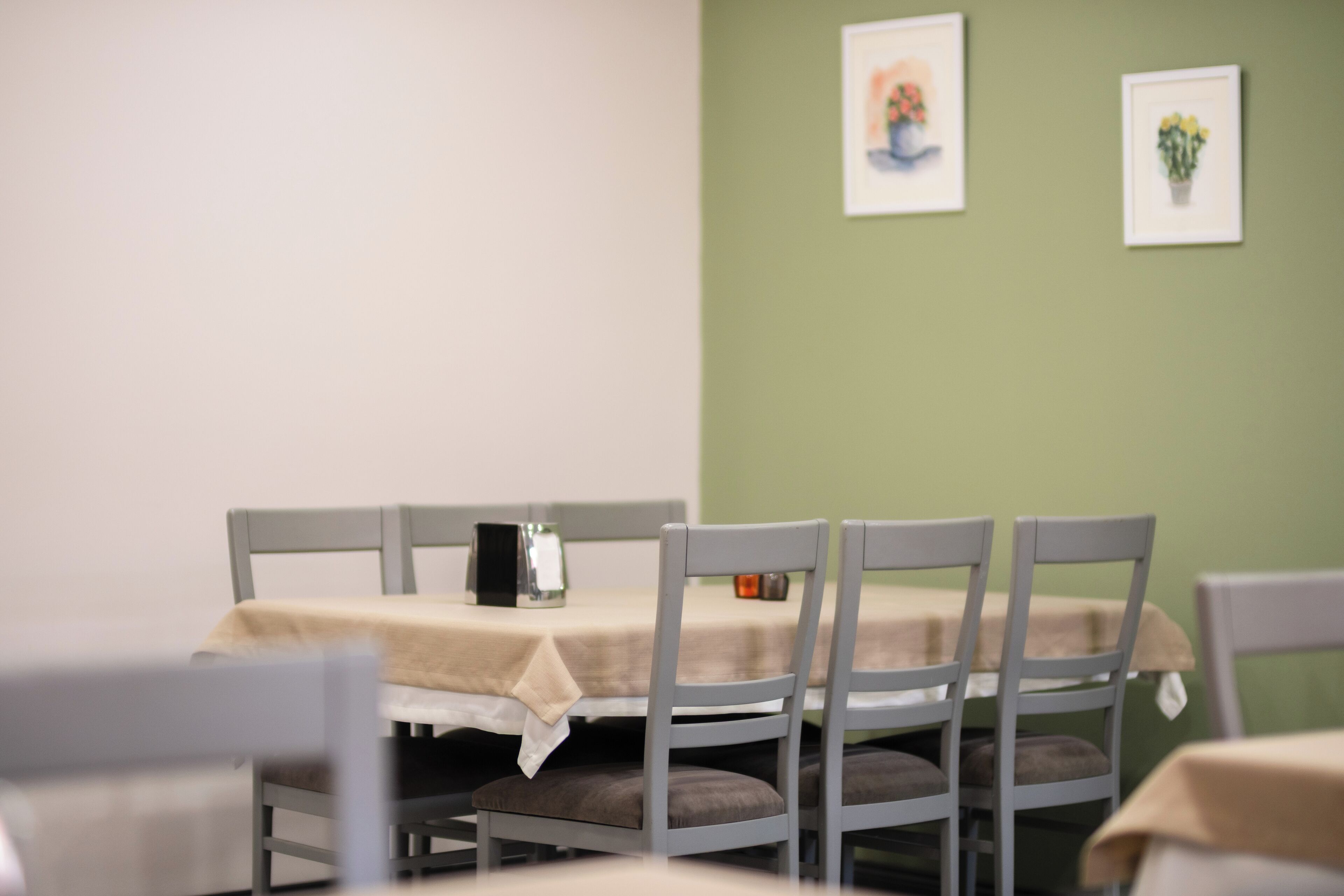 A dining area with a table set for four, chairs, and a tablecloth.