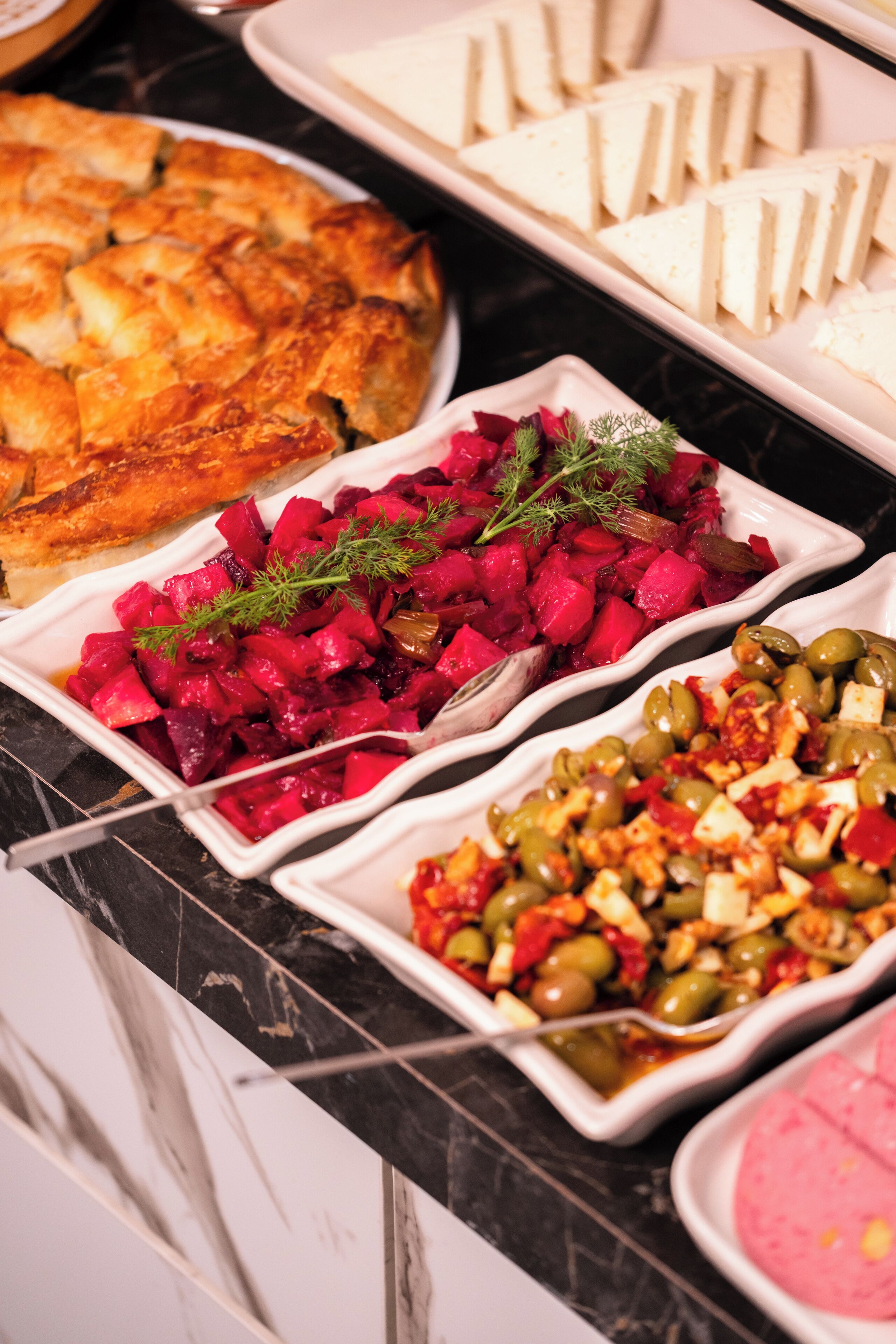Un buffet proposant divers plats, notamment des betteraves, des olives et un plat pané.