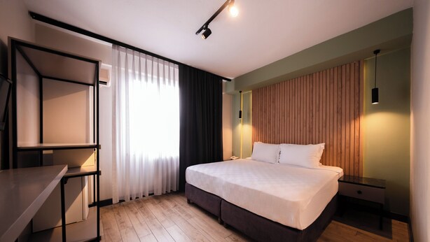 A modern hotel room with a large bed, a desk, and a wardrobe. - Polek Hotel (Çanakkale)