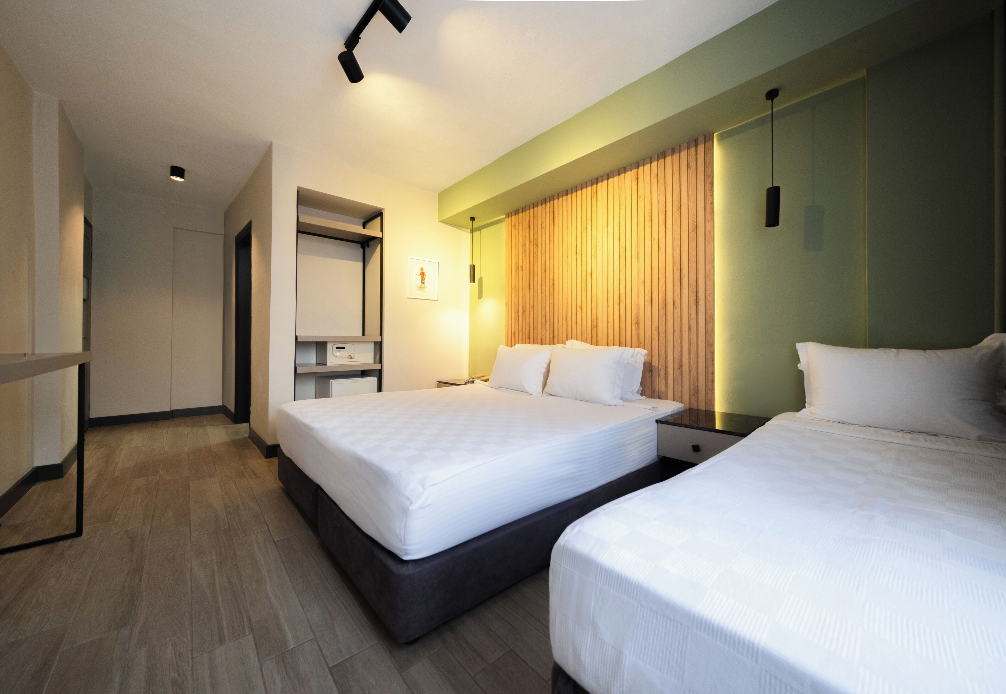 A hotel room with two beds, a wardrobe, a desk, and a mirror.
