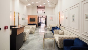 A hotel lobby with a reception desk, seating area with sofas, a TV screen, and a staircase leading to an upper level. - Polek Hotel (Çanakkale)