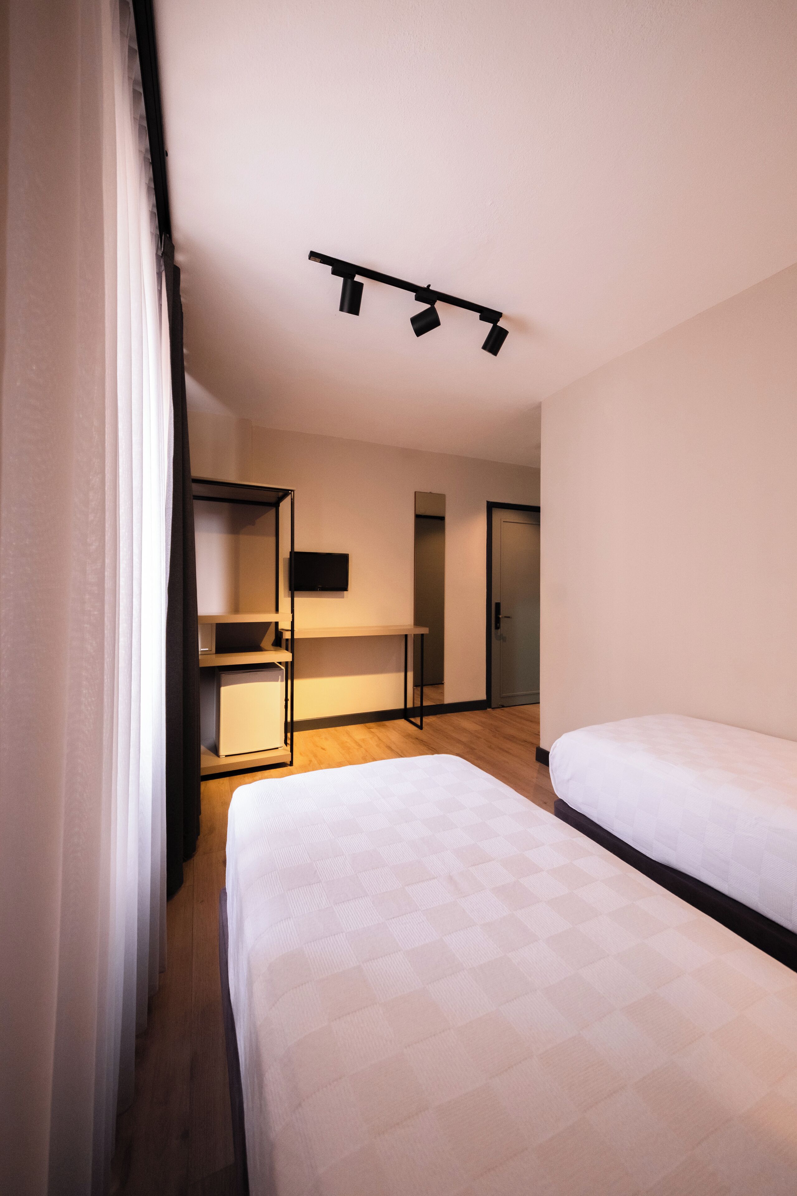 A hotel room with two beds, a desk, a television, and a wardrobe.