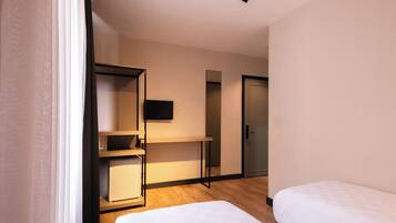 A hotel room with two beds, a desk, a television, and a wardrobe.