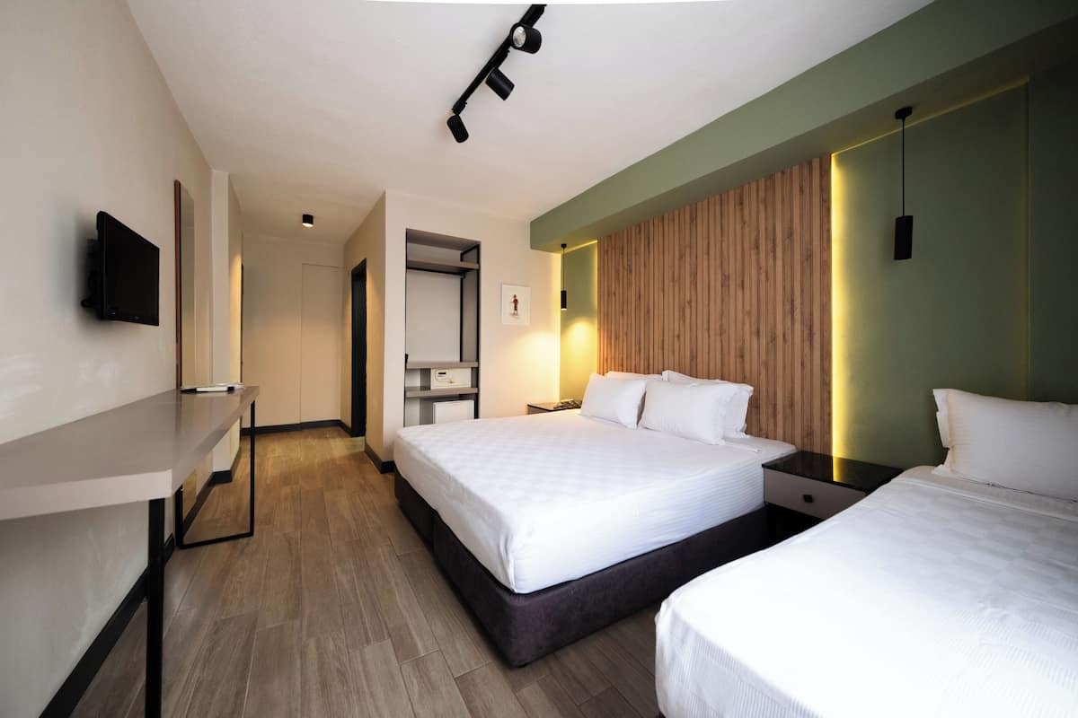 A modern hotel room with a large bed, bedside tables, a flat-screen TV, and a wooden accent wall.