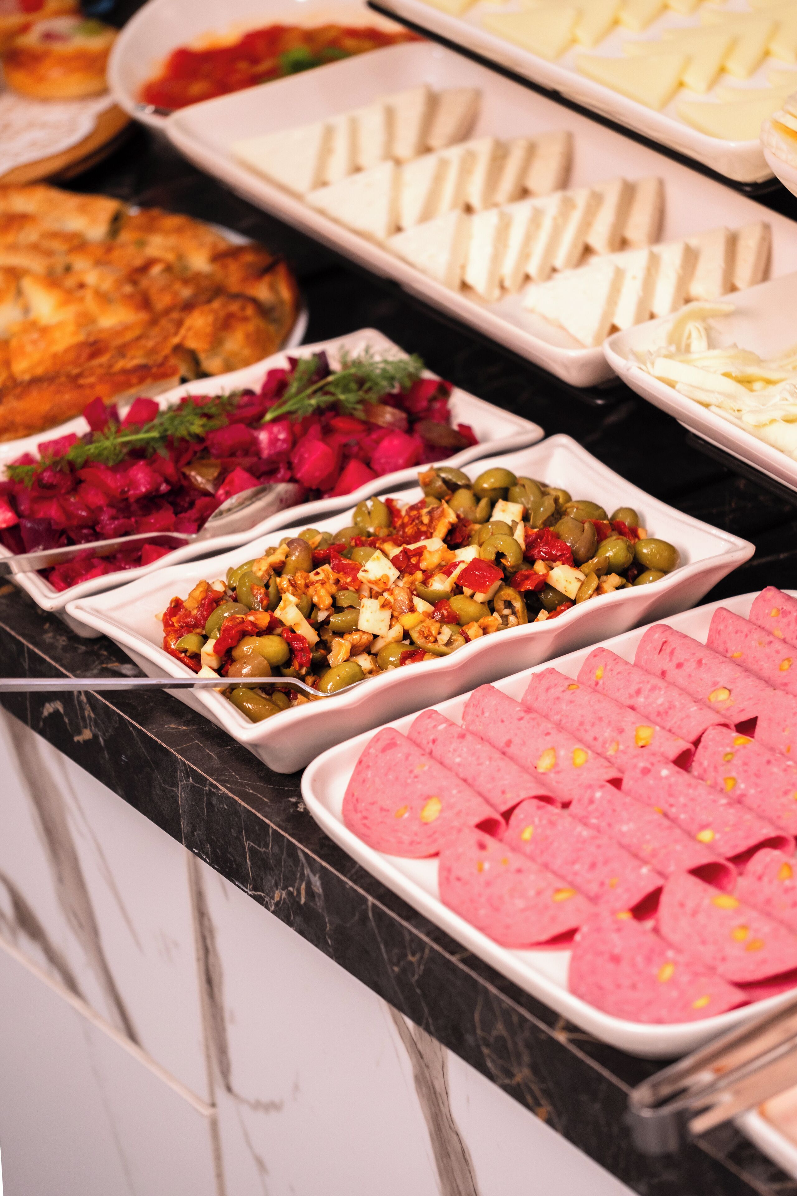 Un bufé con diferentes opciones de comida, incluyendo ensaladas, quesos y carnes.