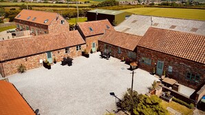 Un patio con edificios de ladrillo, mobiliario exterior y vistas al campo circundante.