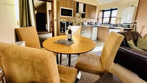 Una cocina moderna con armarios de madera, un comedor con una mesa redonda y sillas, y una sala de estar con sofá.