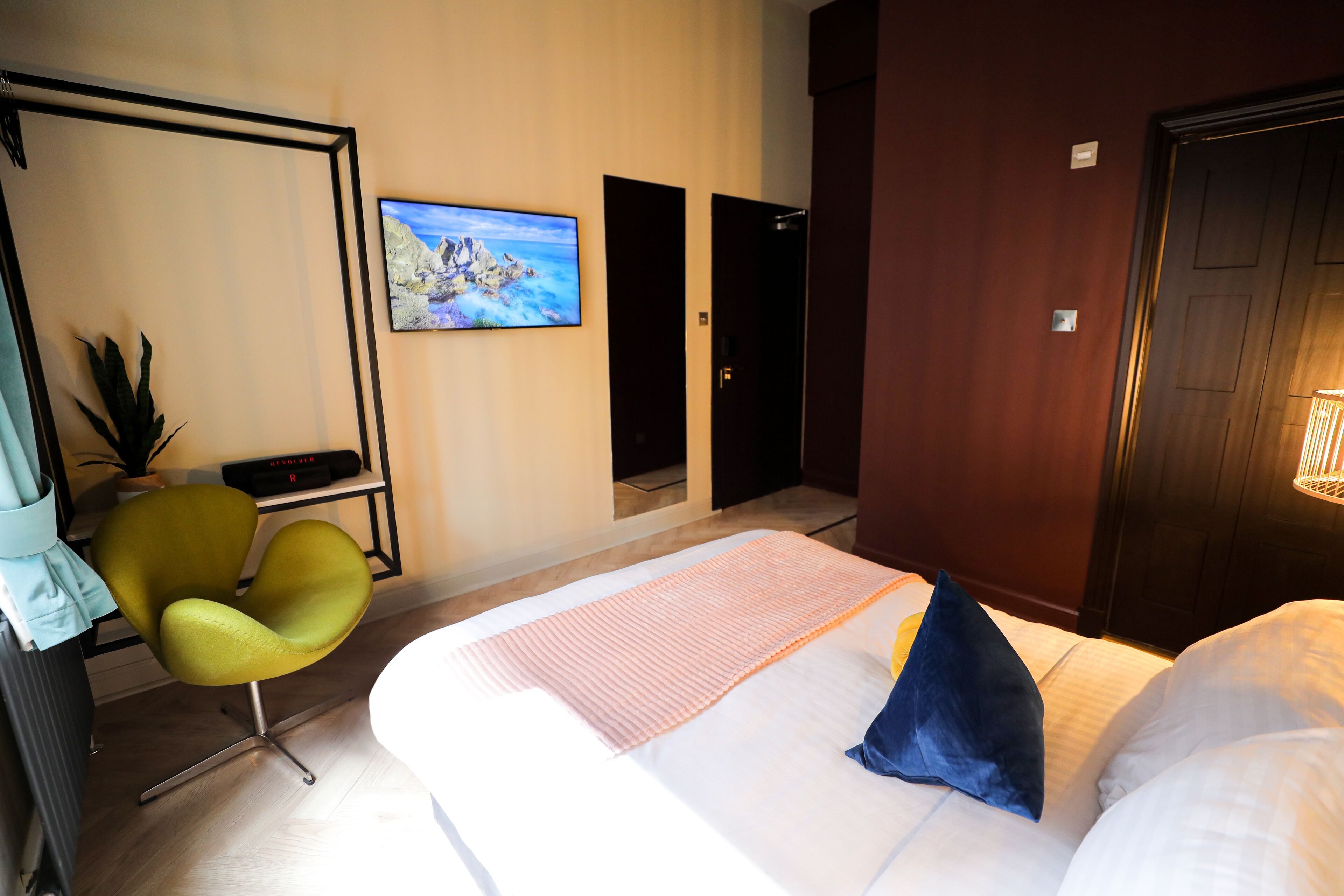 A hotel room with a bed, a desk with a chair, a television, and a door.
