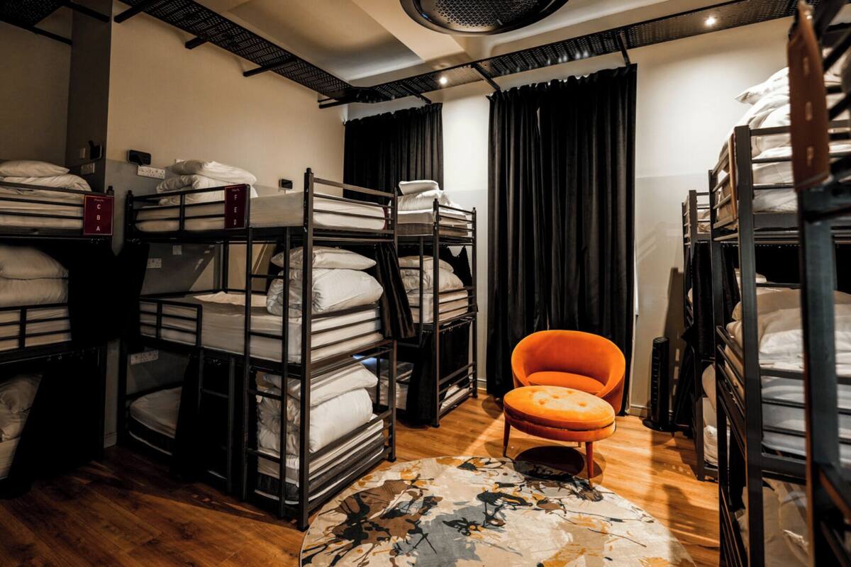Ein Schlafsaalzimmer mit Etagenbetten, einem Stuhl und einem gemusterten Teppich.
