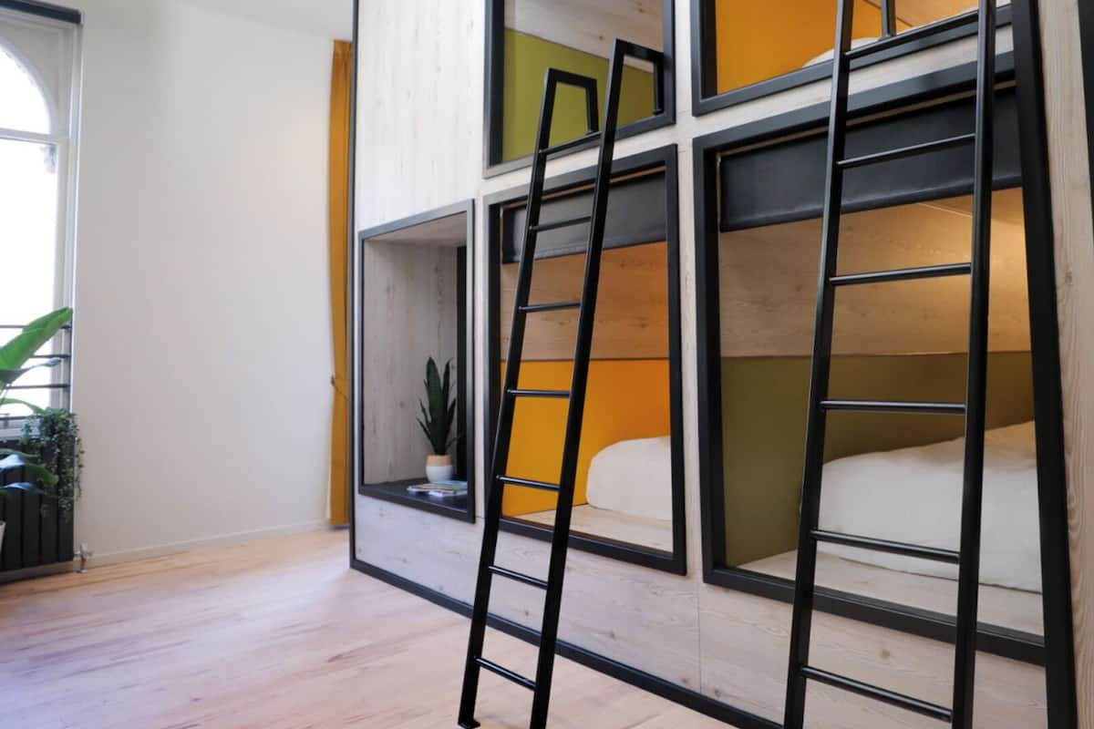 Ein Mehrstockzimmer mit Stockbetten, einer Leiter und einem Blumentopf.